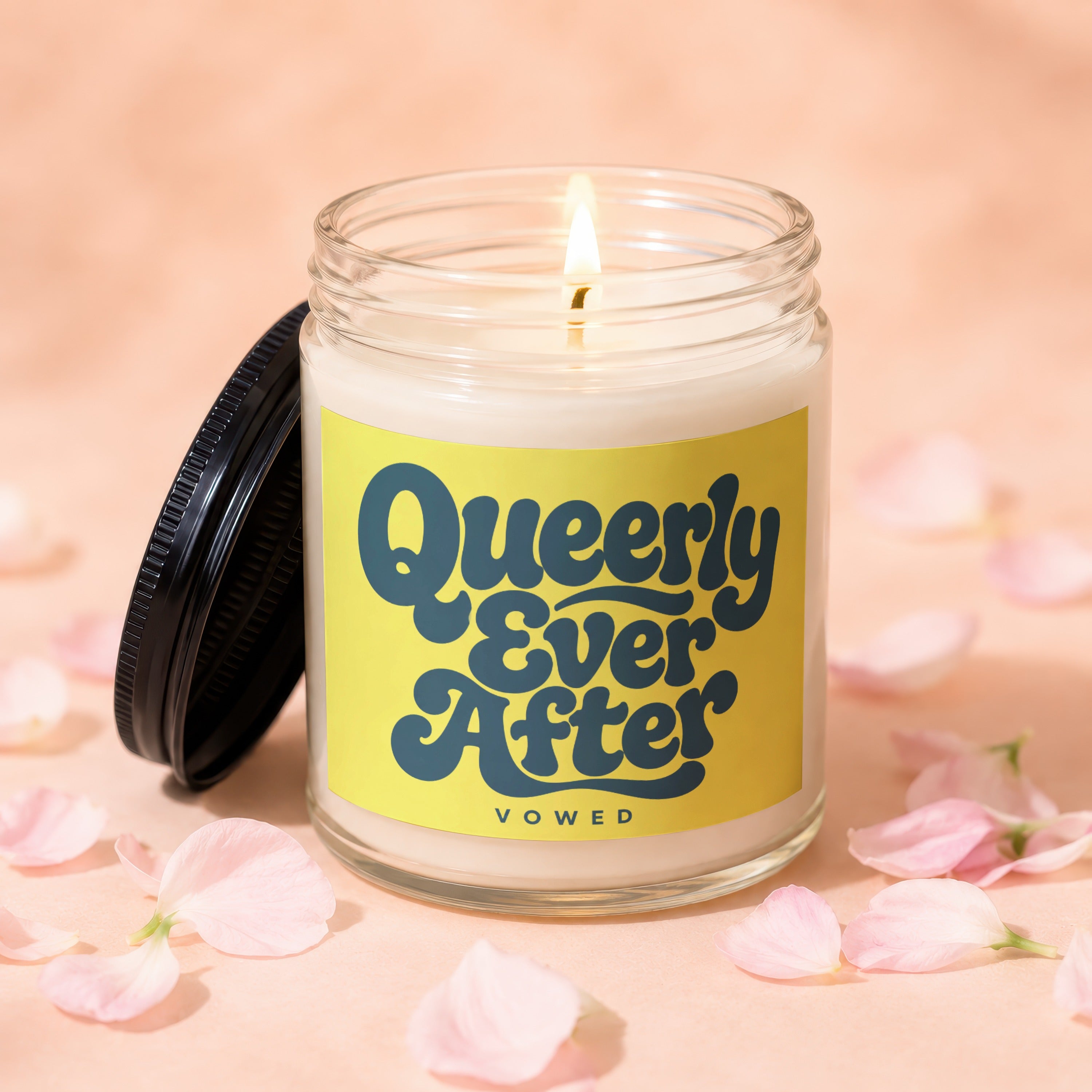 Candle with burning wick, yellow label reading "Queerly Ever After" and "VOWED".