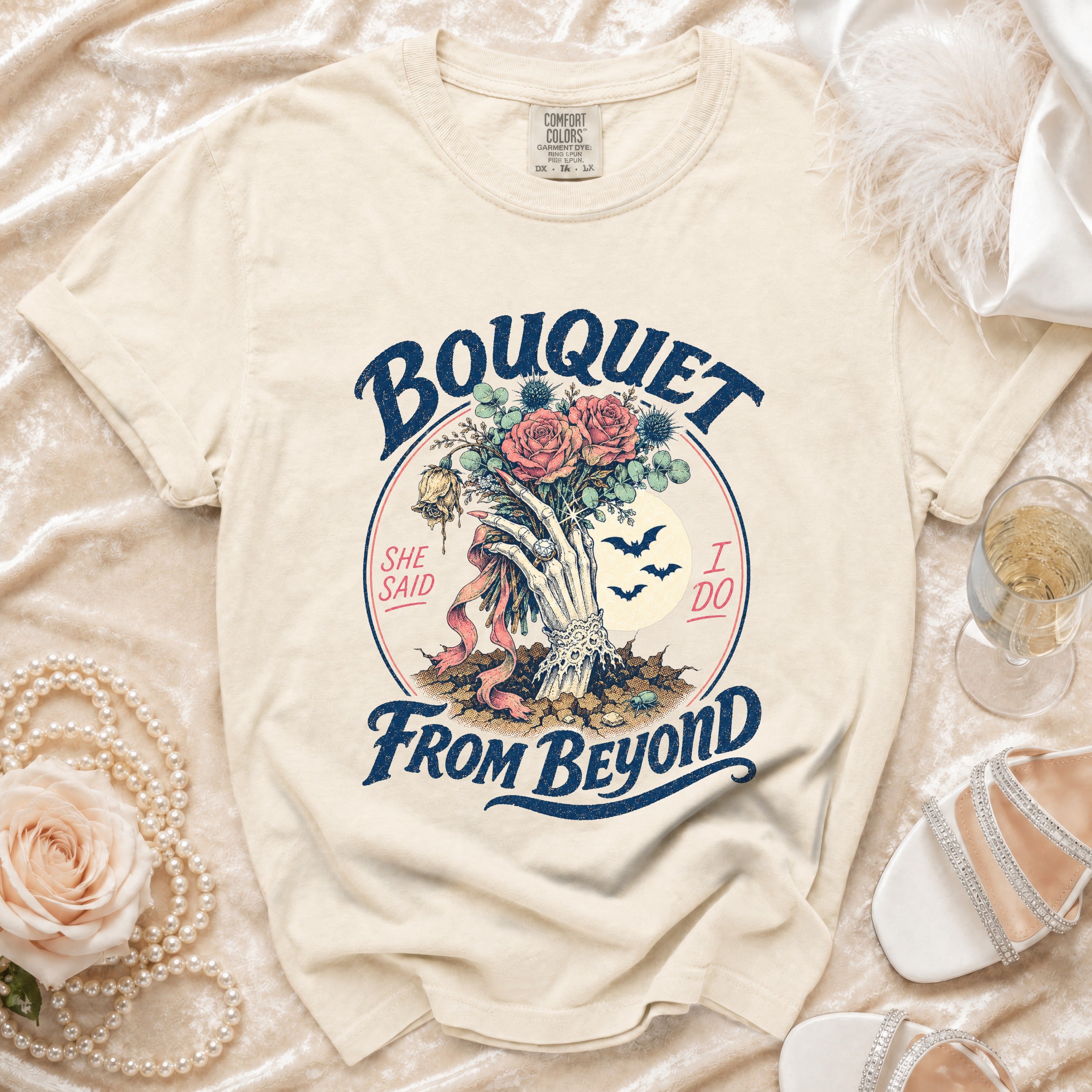 Cream t-shirt with "Bouquet From Beyond" skeleton hand and roses graphic.