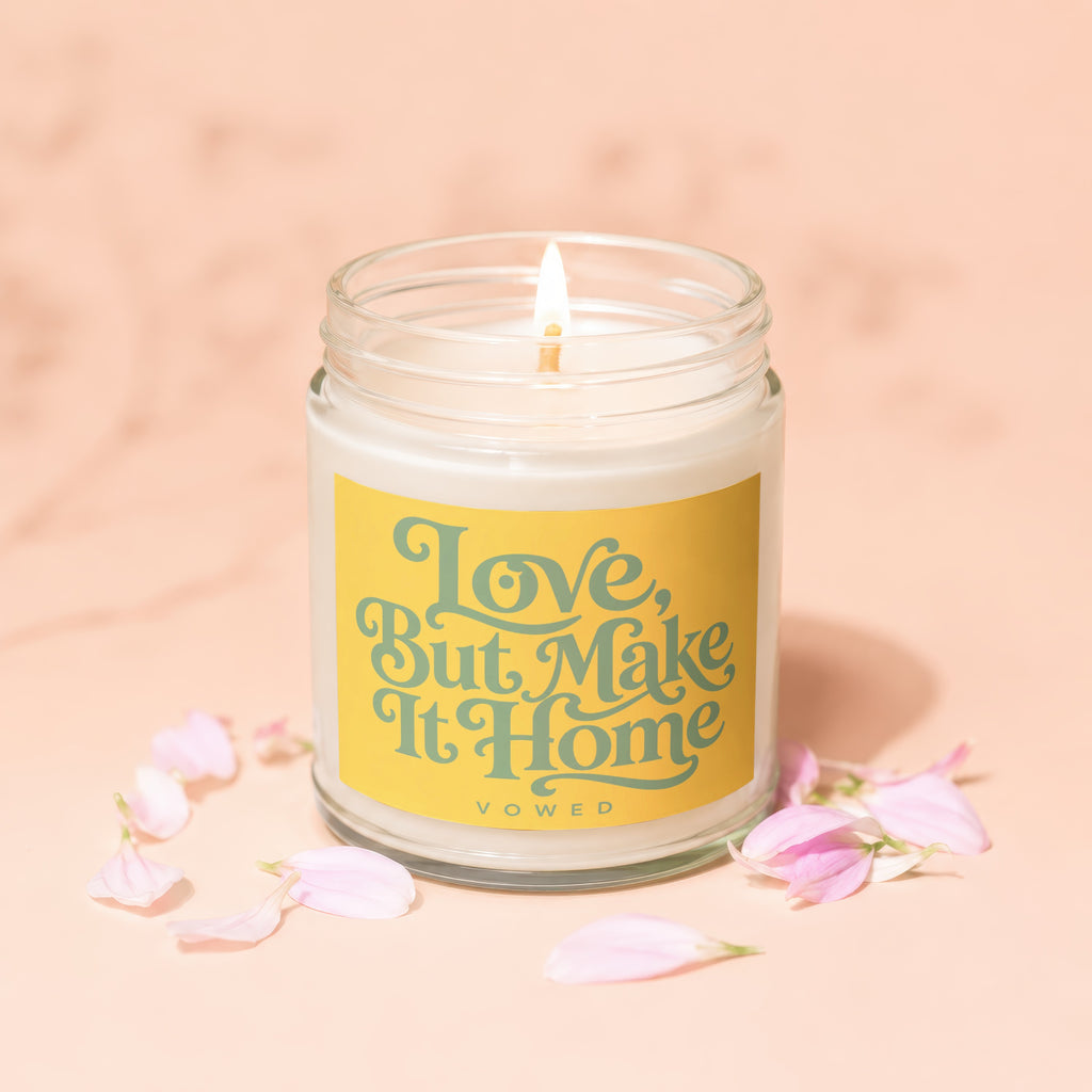 Glass jar candle with yellow label that reads "Love, But Make It Home"