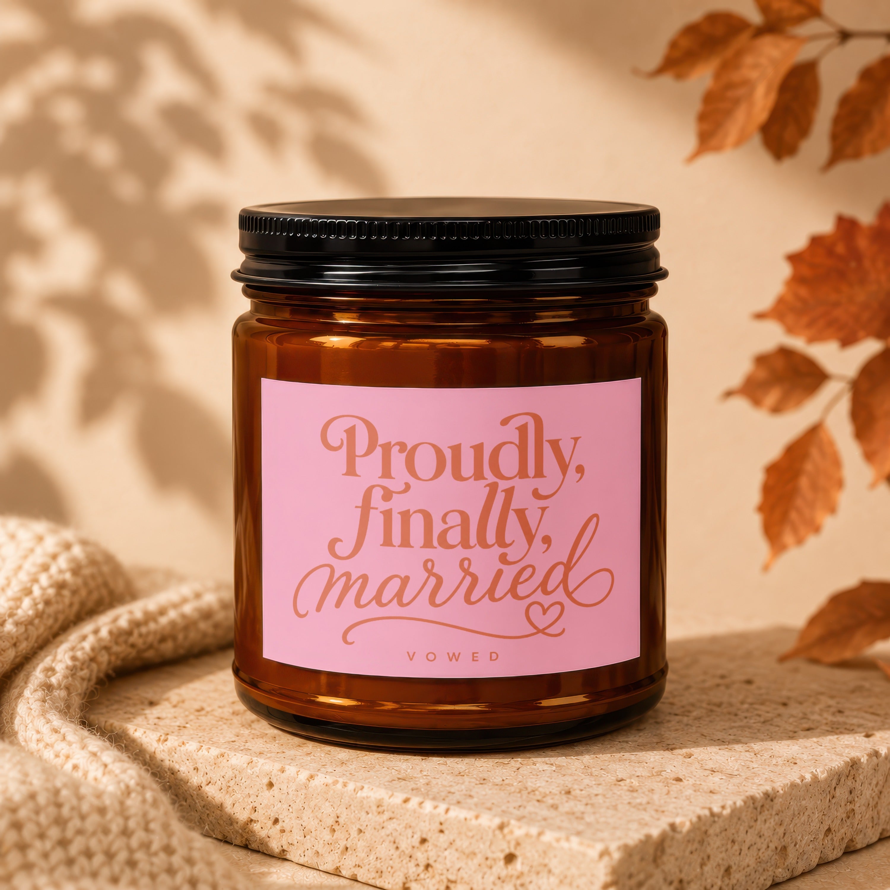 Brown glass candle with pink label reading "Proudly, finally, married".