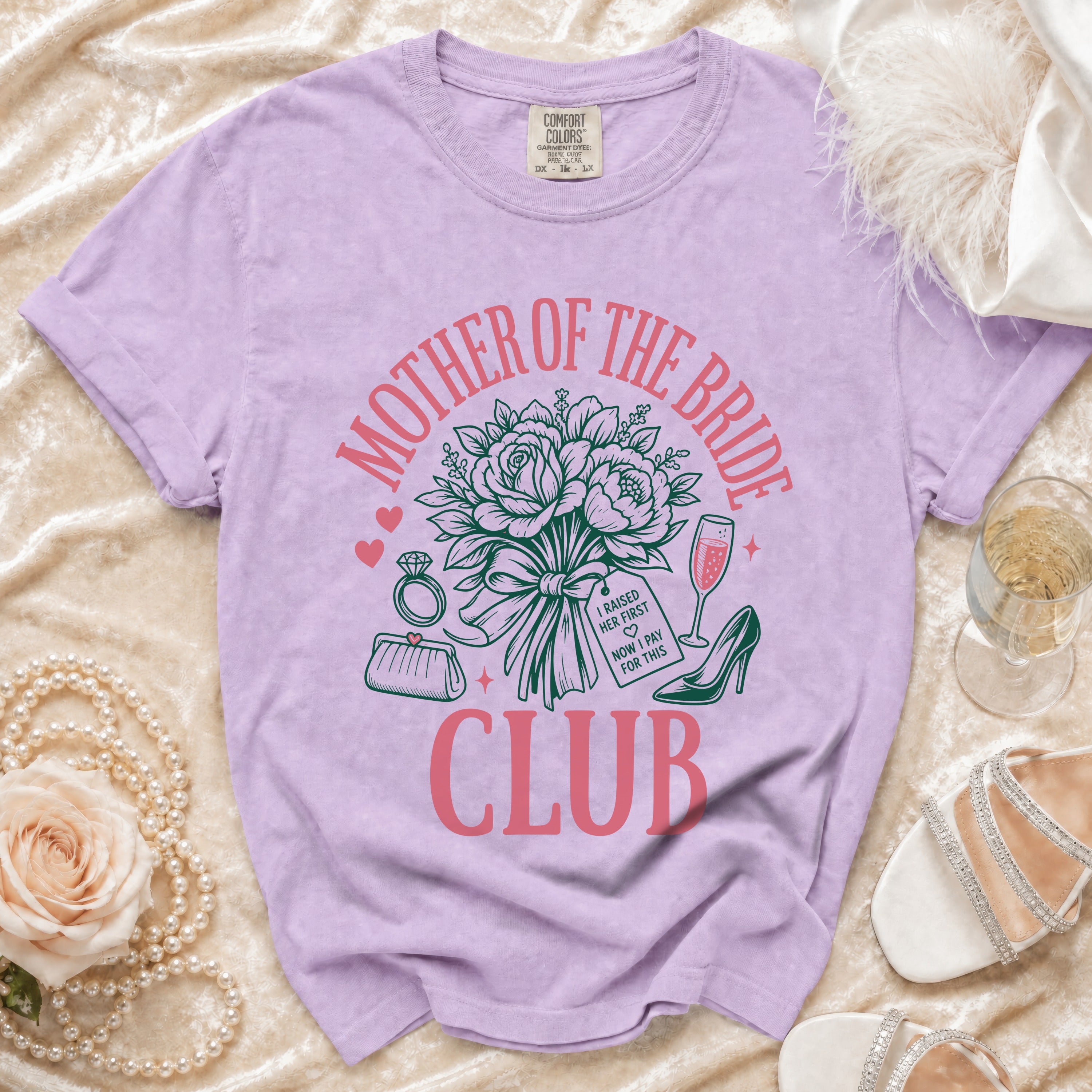 Purple t-shirt with "Mother of the Bride Club" graphic featuring flowers, ring, purse, and high heel.