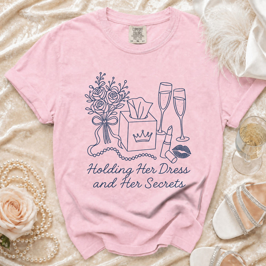 Pink t-shirt with navy line art of flowers, tissue box, champagne, lipstick, and text.