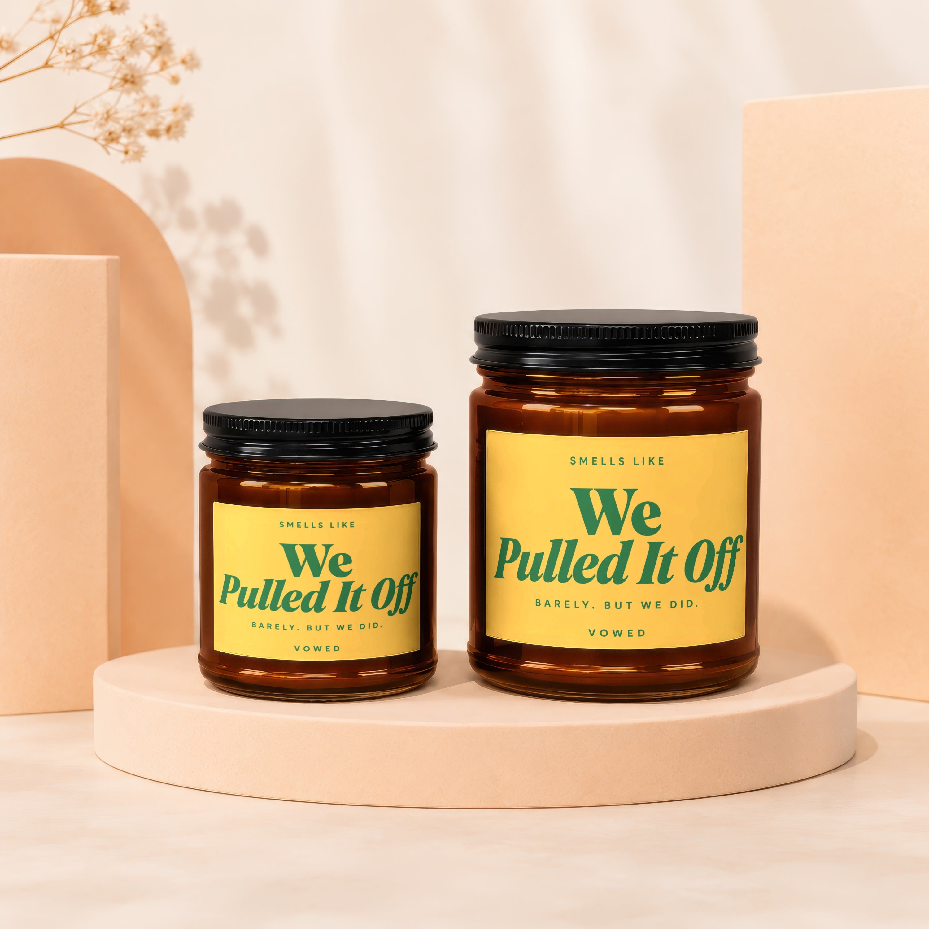 Two amber glass candles with yellow labels reading "We Pulled It Off."