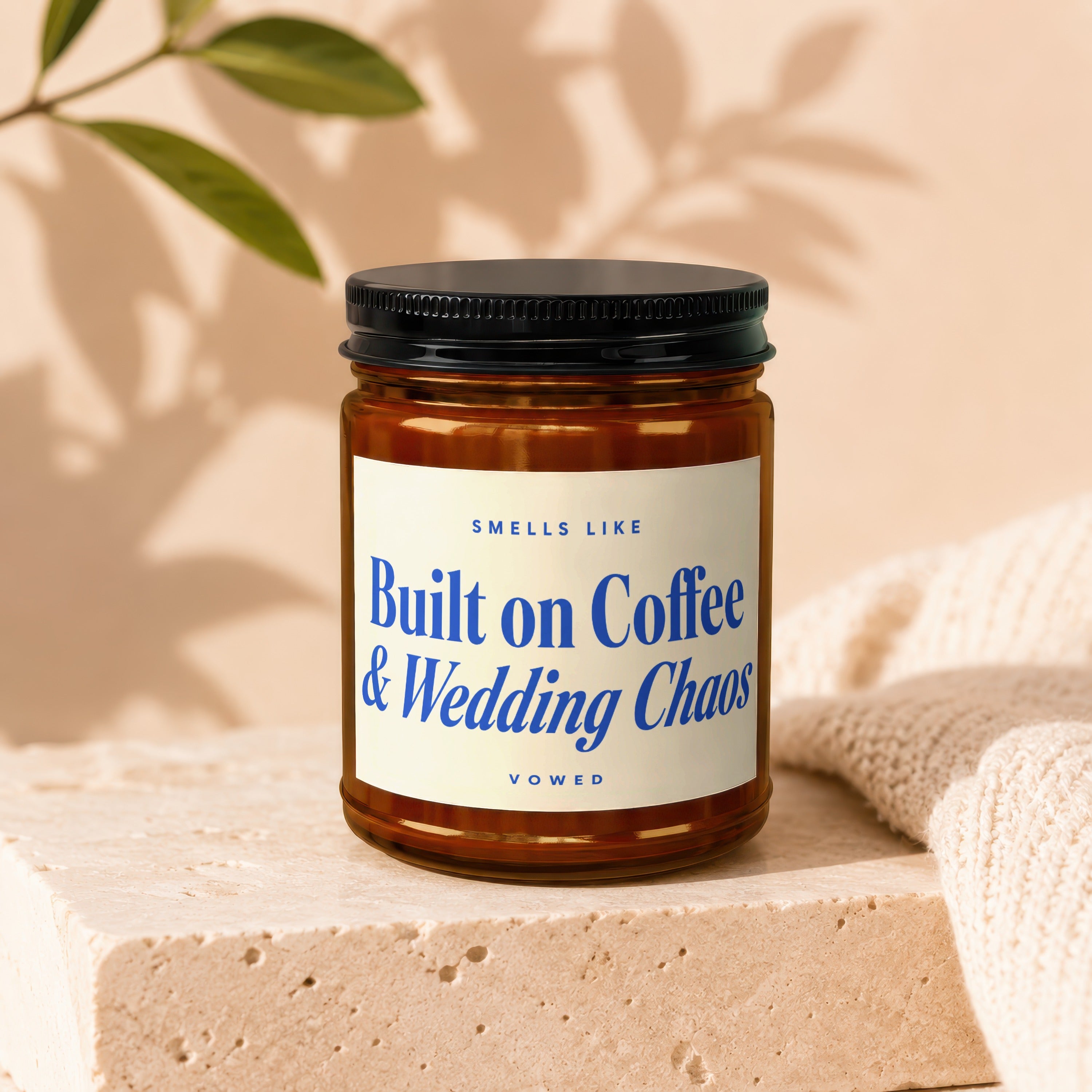 Amber candle with blue text reading "Smells like Built on Coffee & Wedding Chaos"