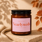 Amber candle with a pink label reading "Smells Like Nearlyweds Save the Date, Someday Vowed".