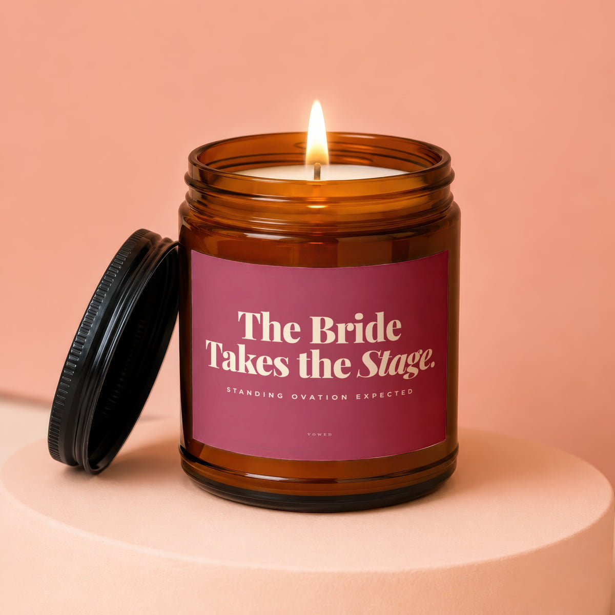 Amber jar candle with lit flame, reading "The Bride Takes the Stage."