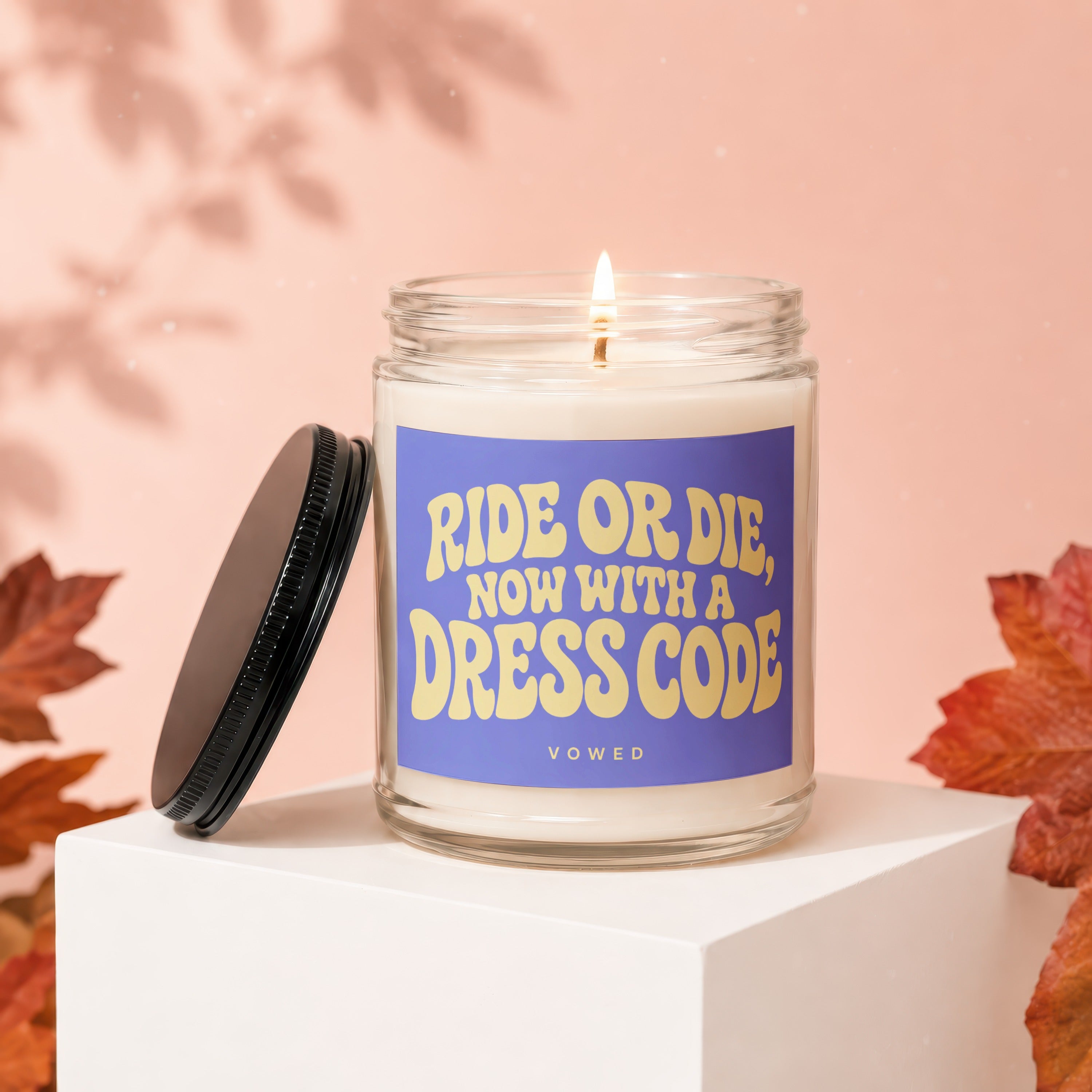 Lit candle in glass jar with "Ride or Die, Now with a Dress Code" label.