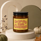 Amber candle in jar with black lid, yellow label reads "Our Love Story Ends Continues".