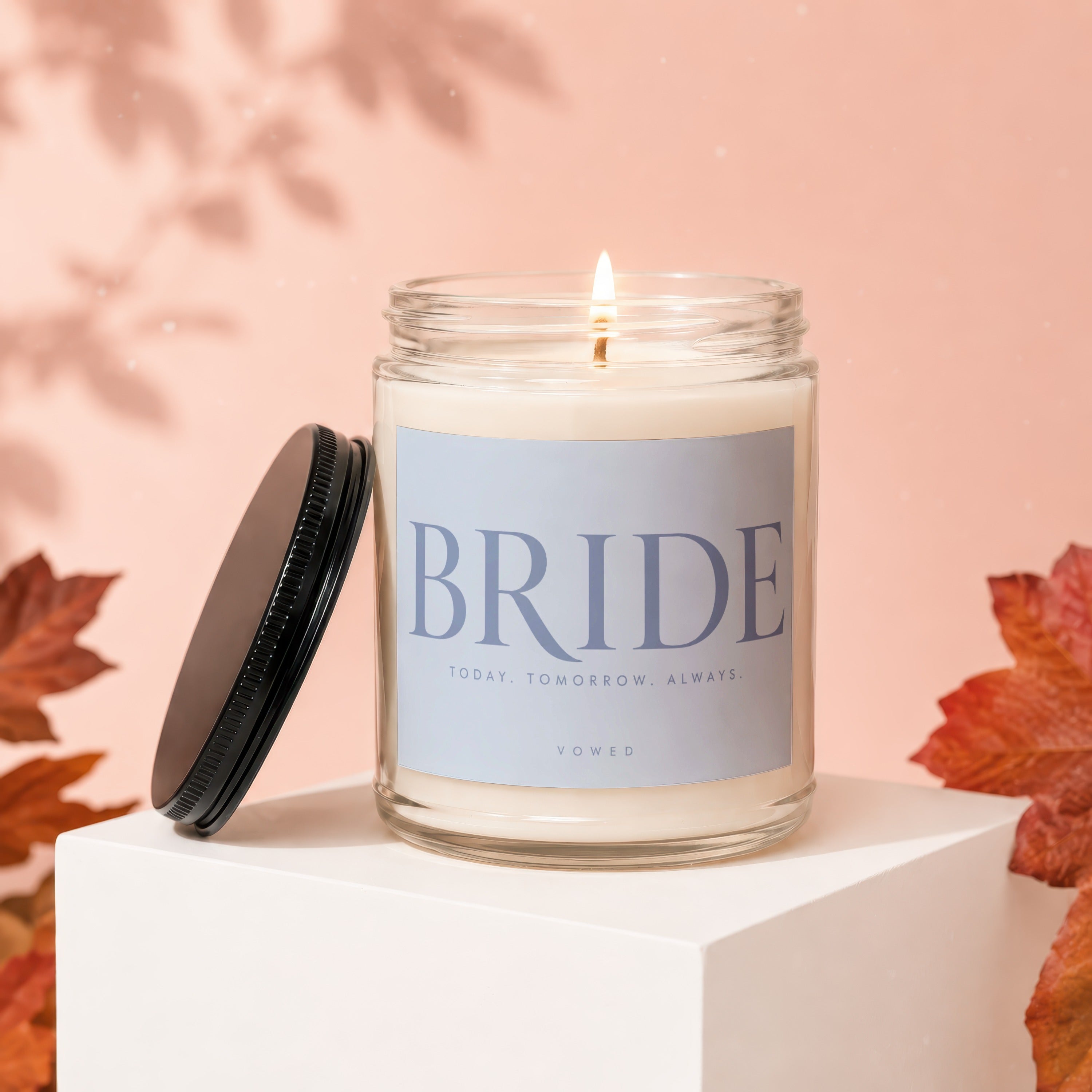 Glass candle with "BRIDE" text, lit wick, and lid off.