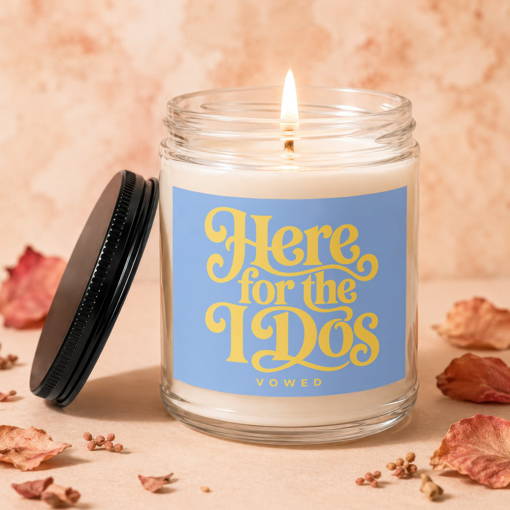 Glass candle with lit wick, and blue label reading "Here for the 190s VOWED".
