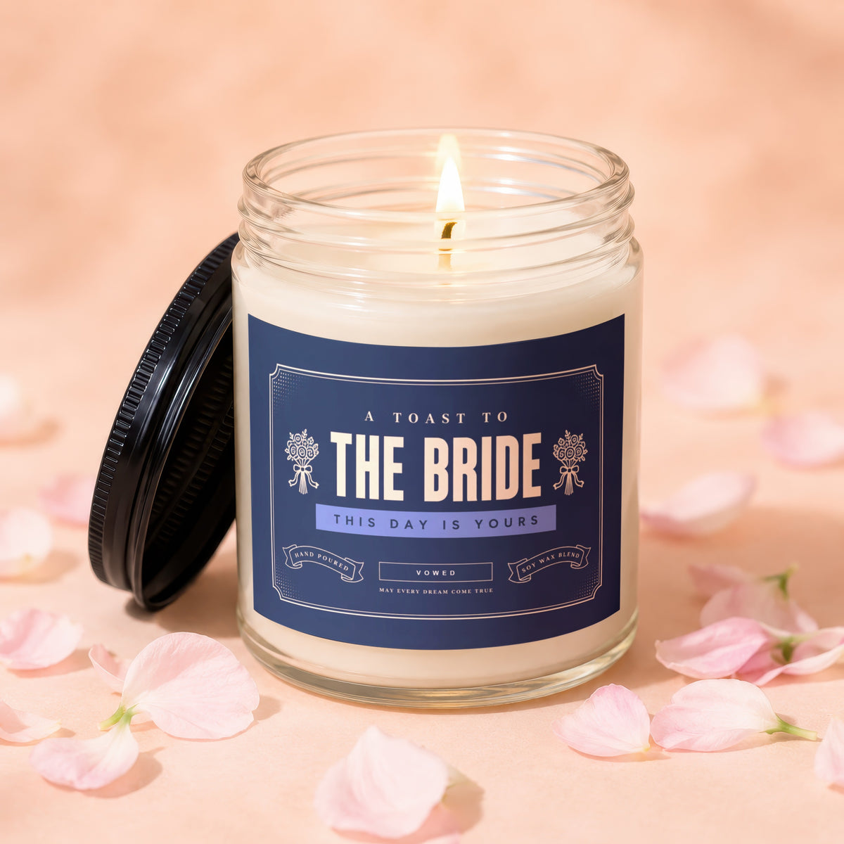 Glass candle with dark lid, lit flame, and "The Bride" text on label.