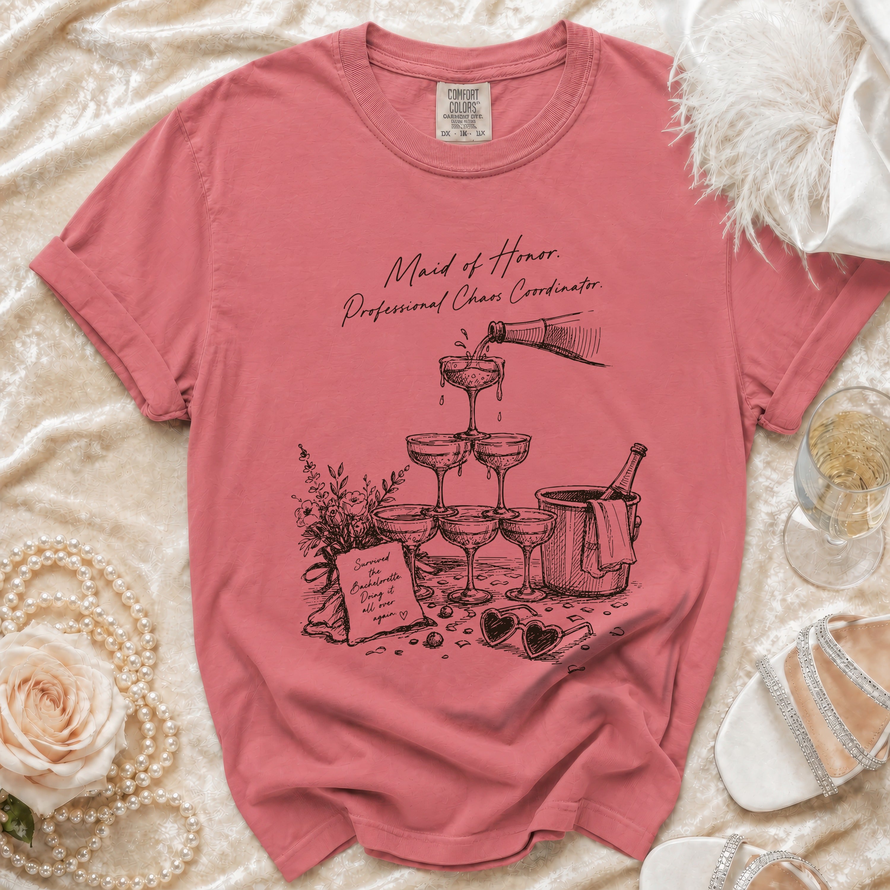 T-shirt with "Maid of Honor. Professional Chaos Coordinator" text and champagne illustration.