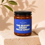Amber jar candle with blue label reading "The Seating Chart Falls Apart".