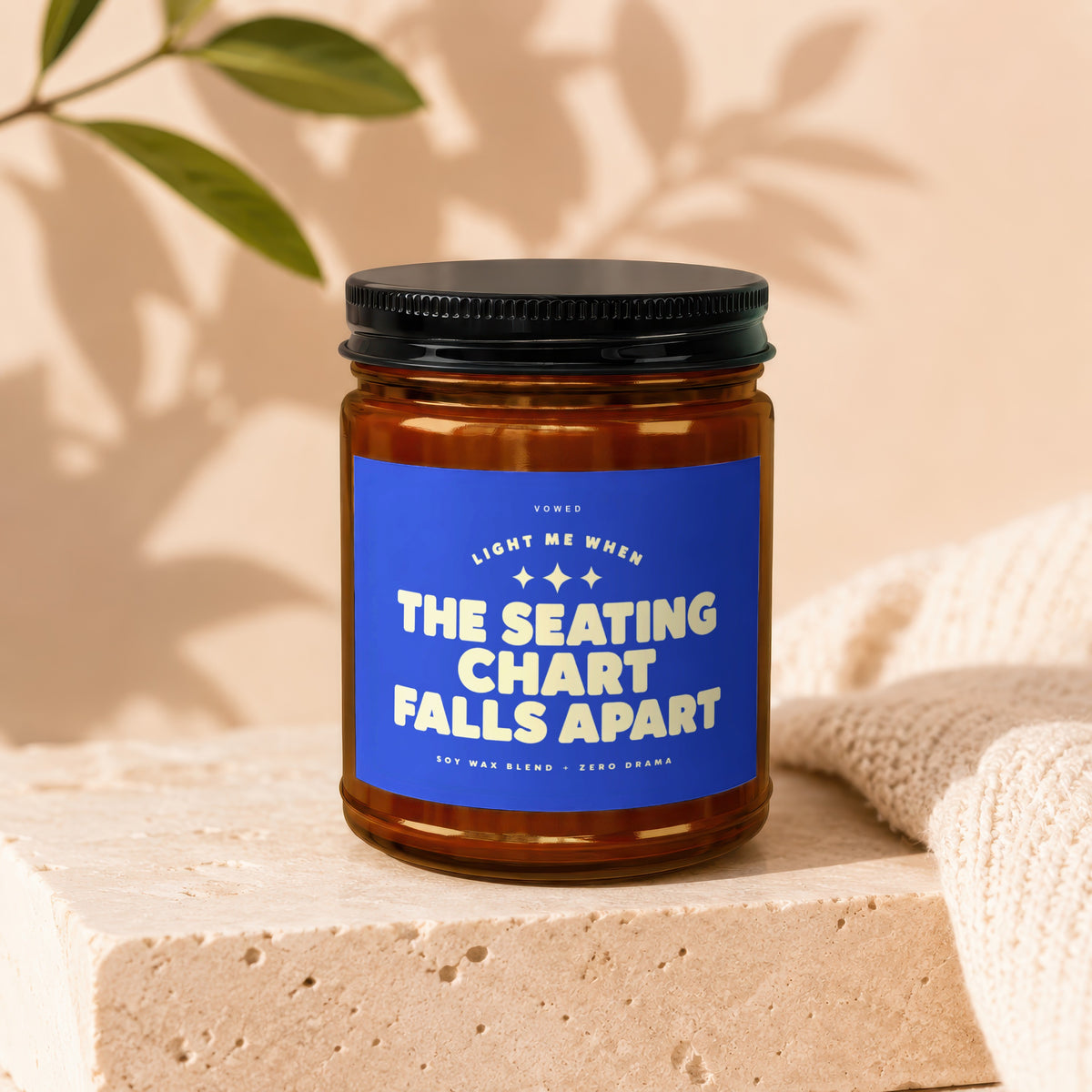 Amber jar candle with blue label reading "The Seating Chart Falls Apart".
