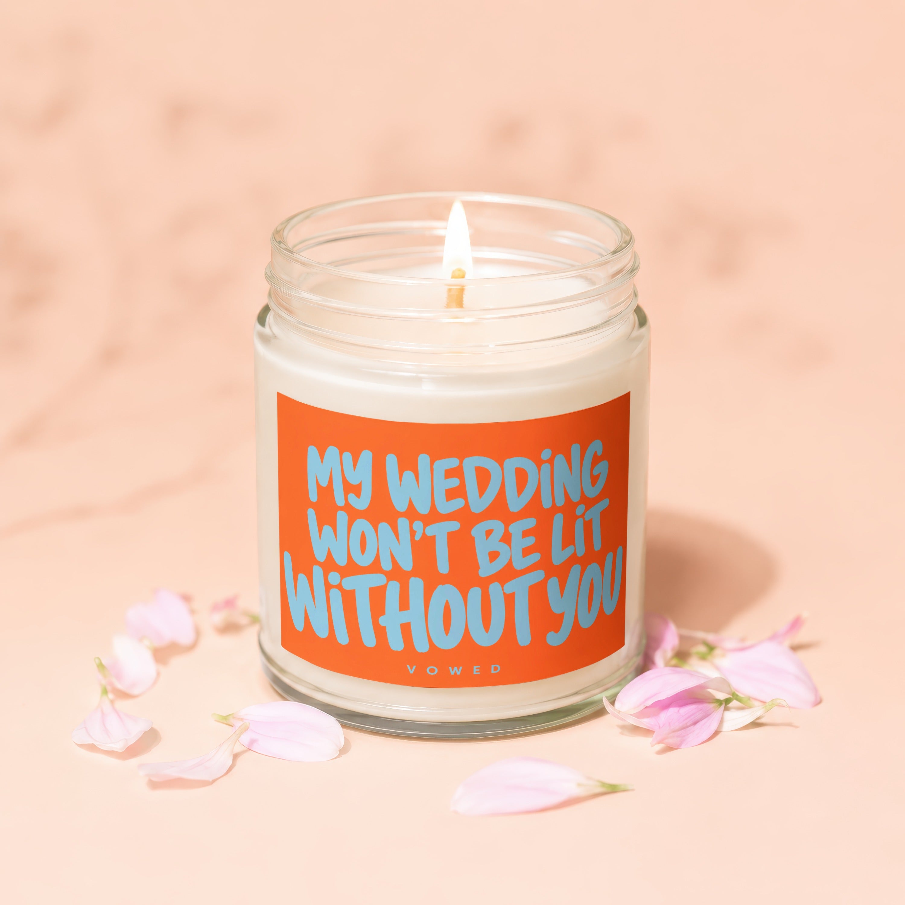 Lit candle in jar with orange label that reads "MY WEDDING WON'T BE LIT WITHOUT YOU."