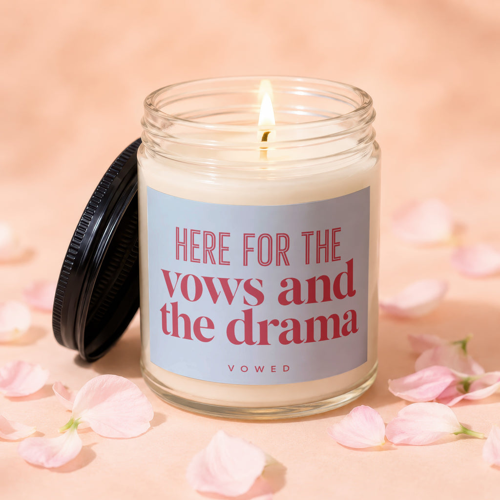 Lit candle in glass jar with black lid, reading "HERE FOR THE vows and the drama VOWED".