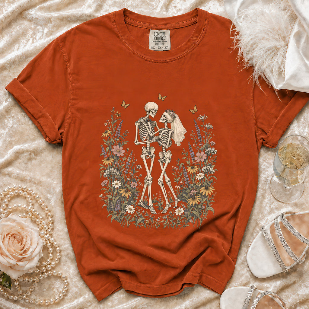 Orange t-shirt with skeleton couple wedding graphic surrounded by flowers.