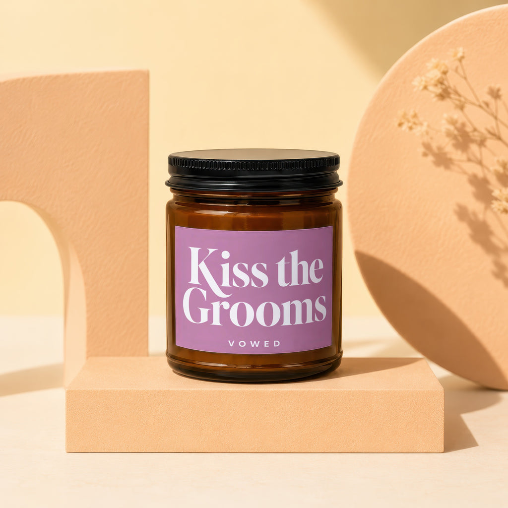 Brown candle in amber jar with "Kiss the Grooms VOWED" label on a pedestal.