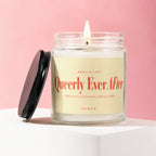 Glass candle with lit wick, reads "Queerly Ever After".