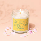 Glass jar candle with burning wick and label stating "Officially Very Into This Vowed".