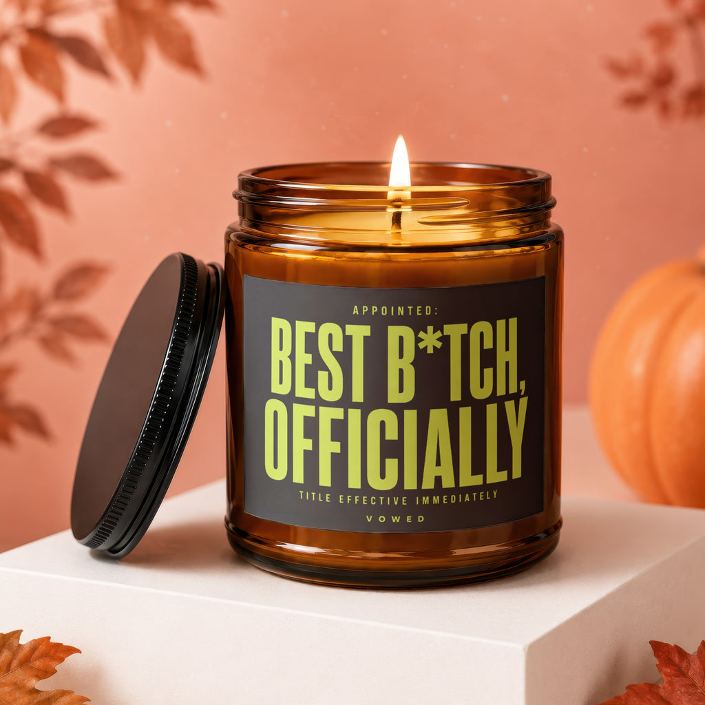 Amber glass candle with "Best B*tch, Officially" text and lit wick.