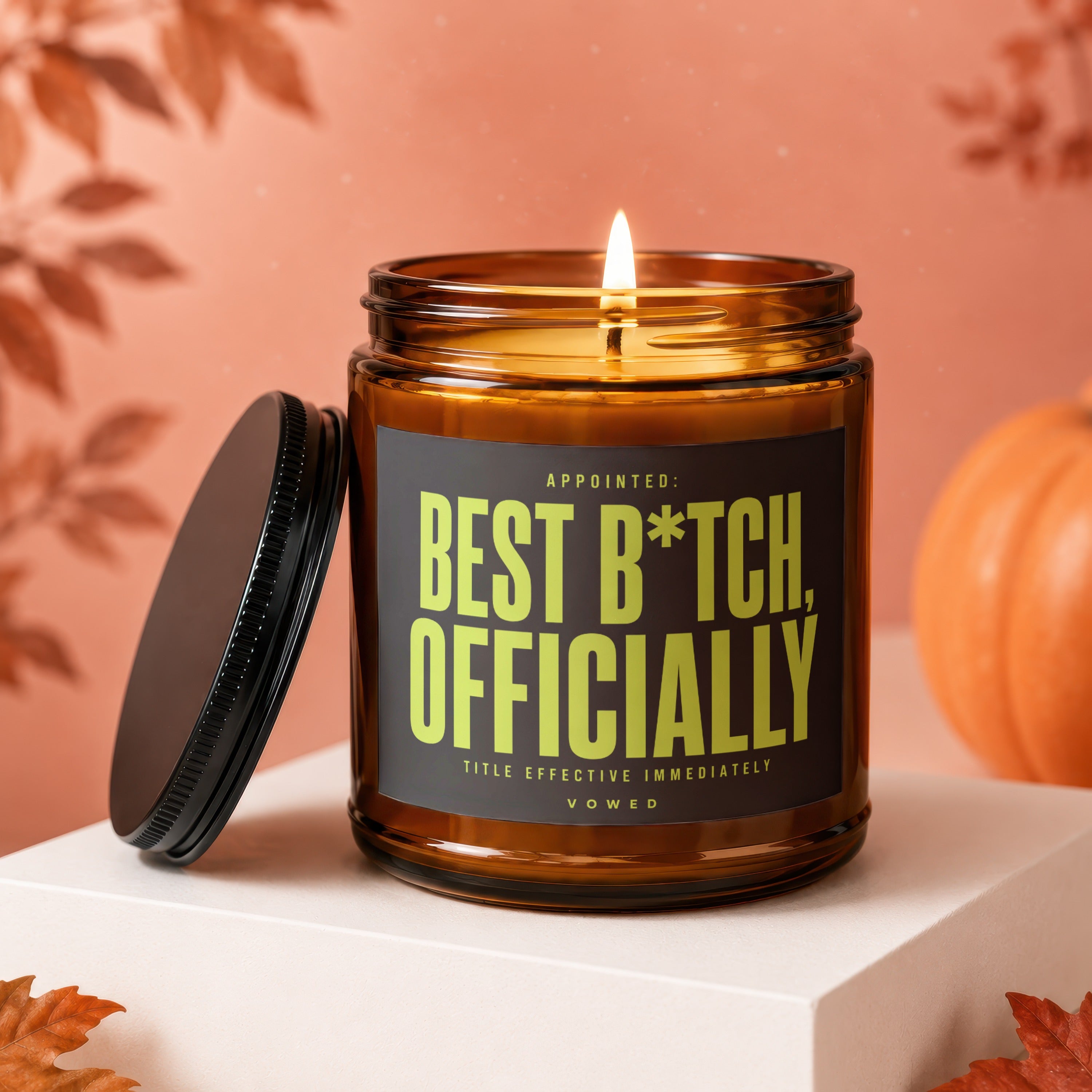 Amber glass candle with "Best B*tch, Officially" text and lit wick.