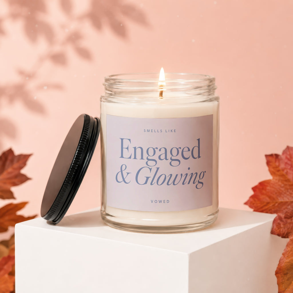 "Engaged & Glowing" candle with a lit wick in a glass jar with lid off.
