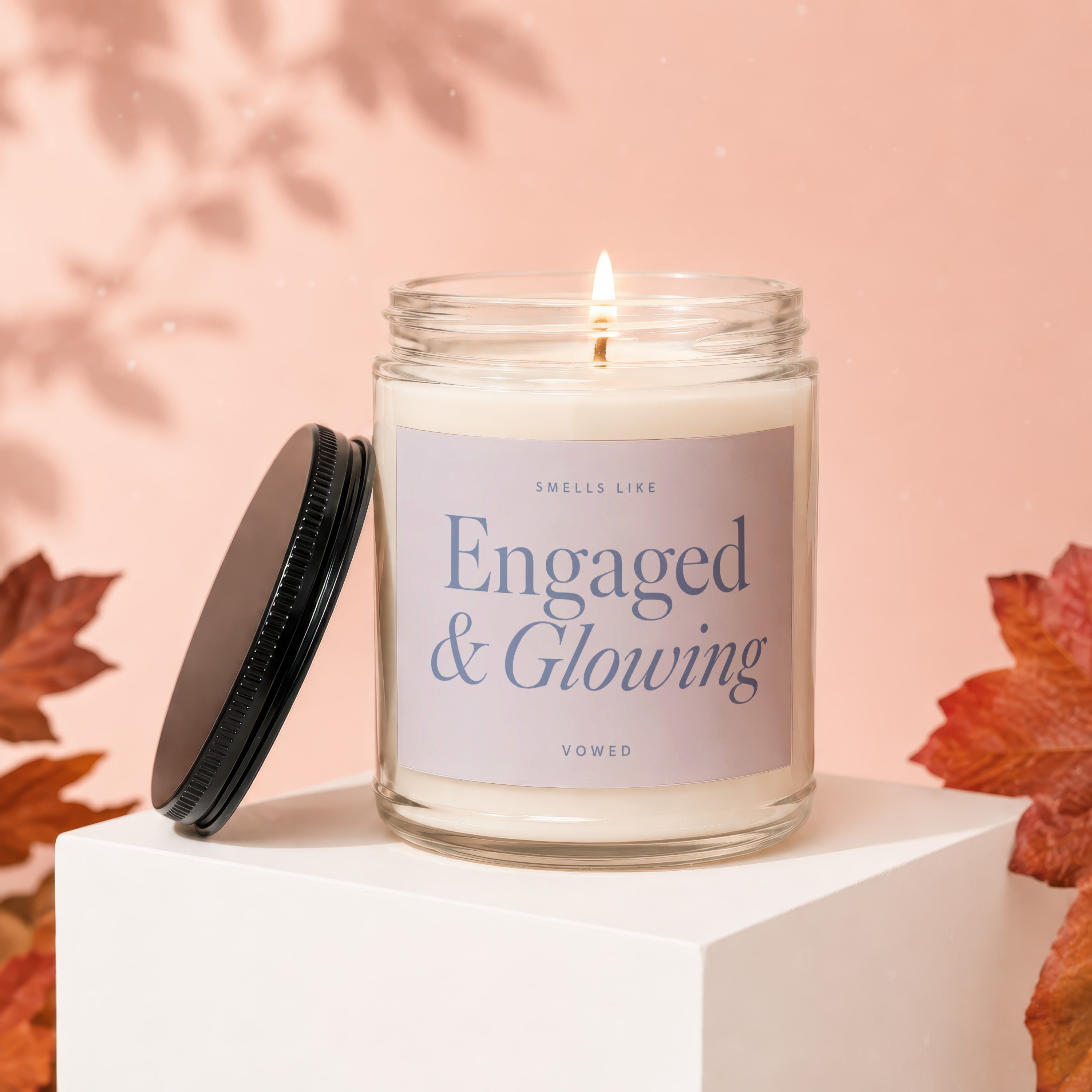 "Engaged & Glowing" candle with a lit wick in a glass jar with lid off.