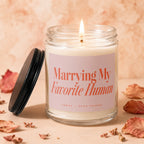 Lit candle in glass jar with "Marrying My Favorite Human" text and lid.