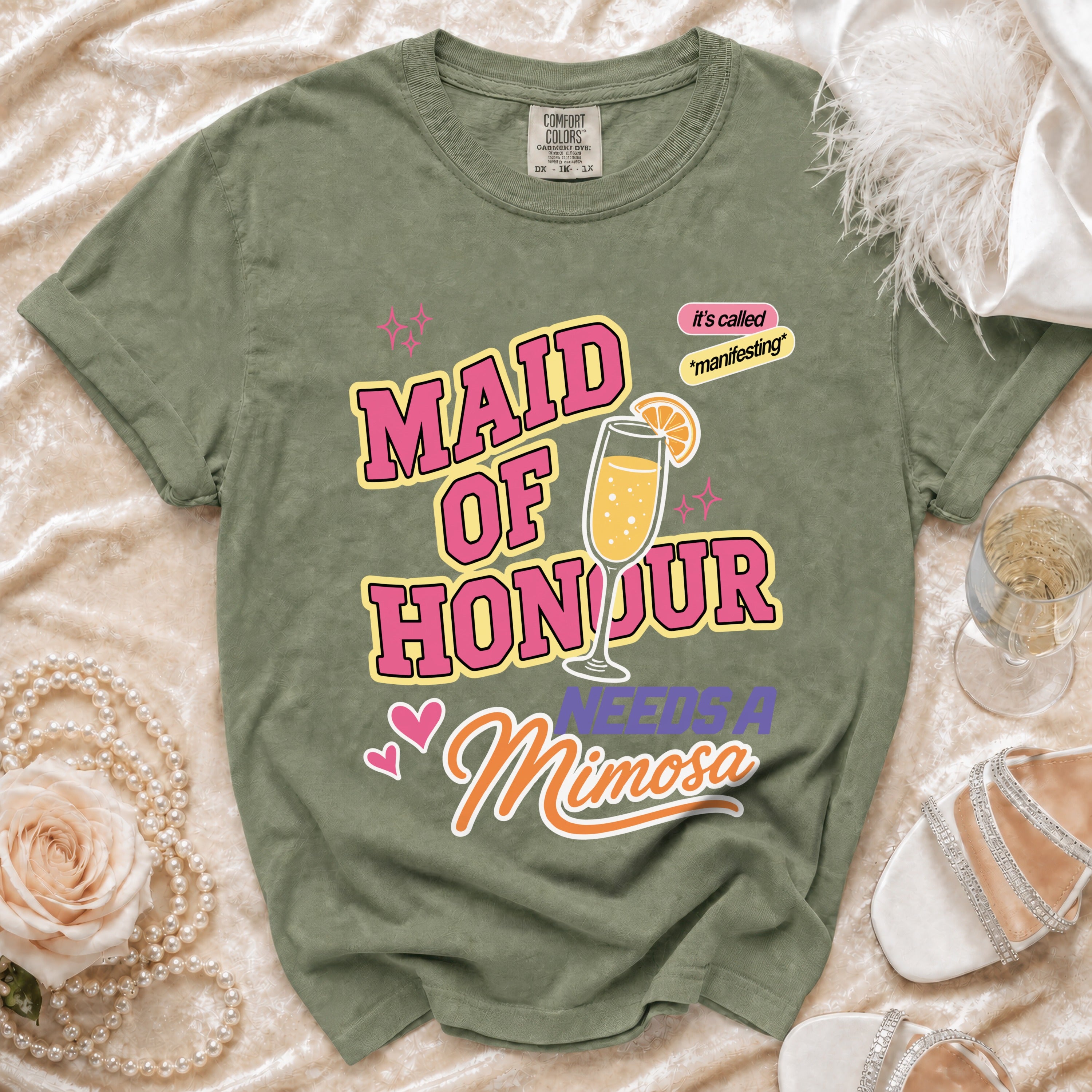 Green t-shirt with "MAID OF HONOUR NEEDS A Mimosa" text and mimosa graphic.