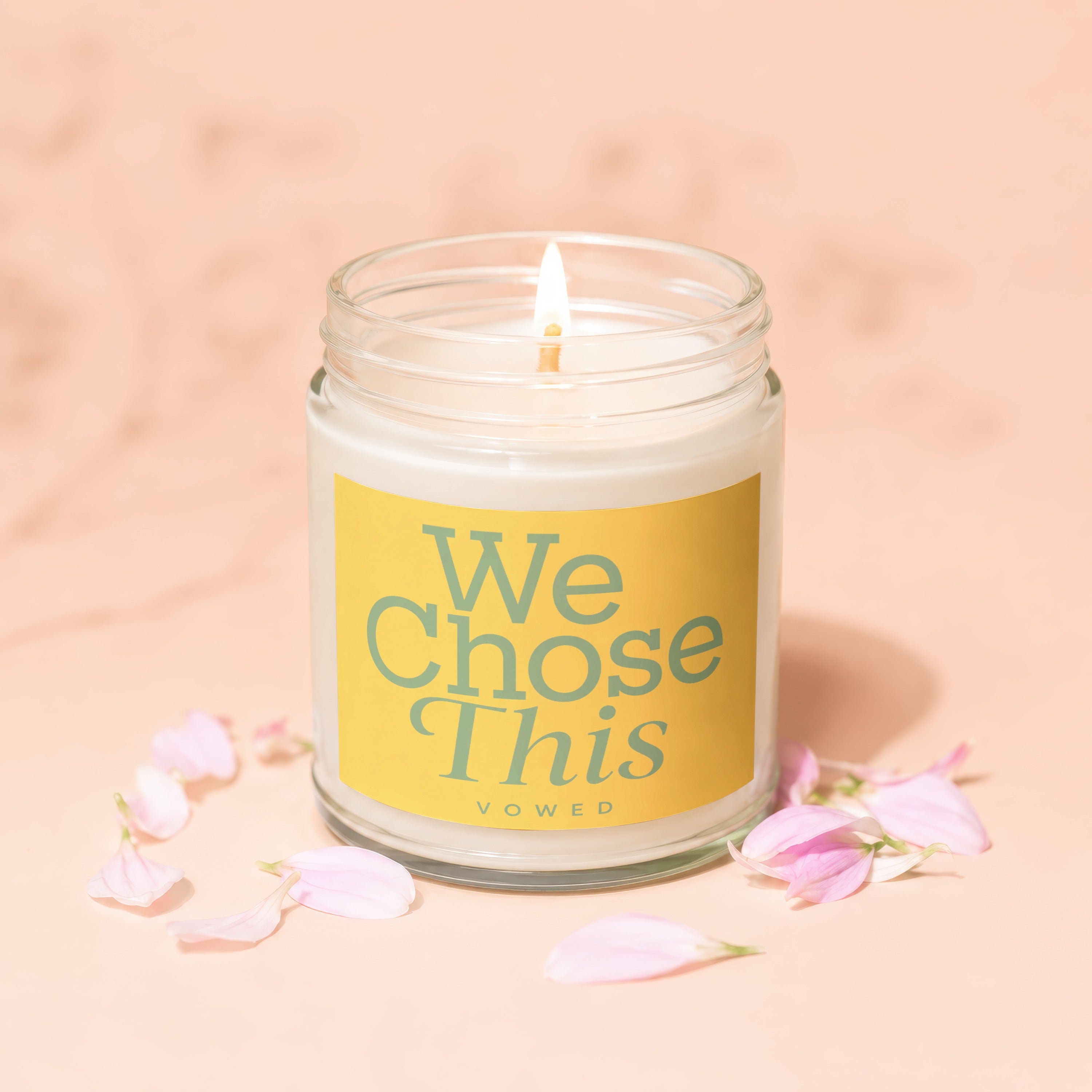 Candle with yellow label reading "We Chose This" surrounded by pink petals.