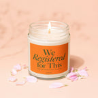 Jar candle with orange label saying "We Registered for This" and a lit wick.