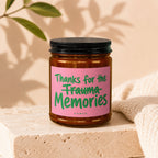 Amber glass candle with pink label that reads "Thanks for the Trauma Memories, Vowed."
