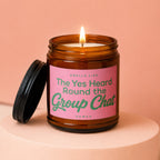 Amber jar candle with lit wick, pink label reads "Smells Like The Yes Heard Round the Group Chat"