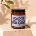 Amber jar candle with a label reading "B*tch, you knew! And still said yes. Vowed."