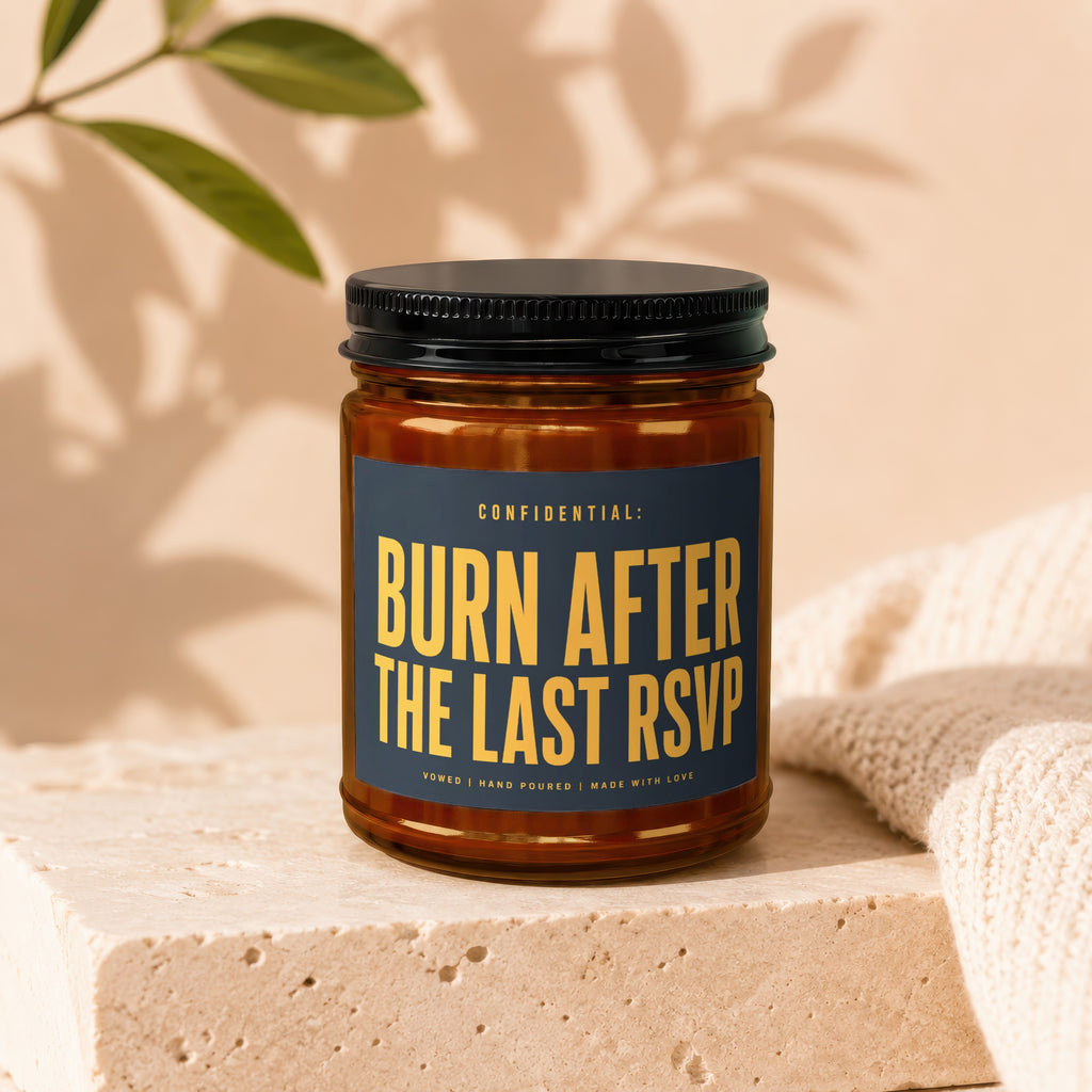 Amber candle with black lid, blue label reads "Burn After The Last RSVP".