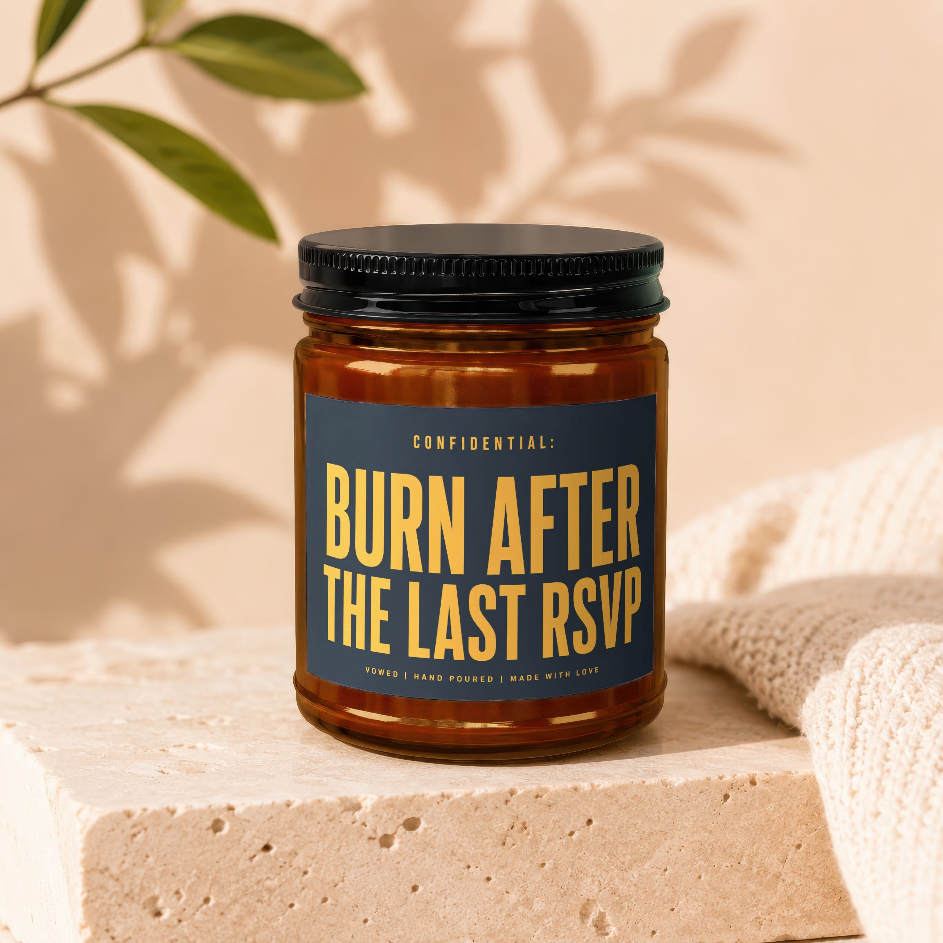 Amber candle with black lid, blue label reads "Burn After The Last RSVP".