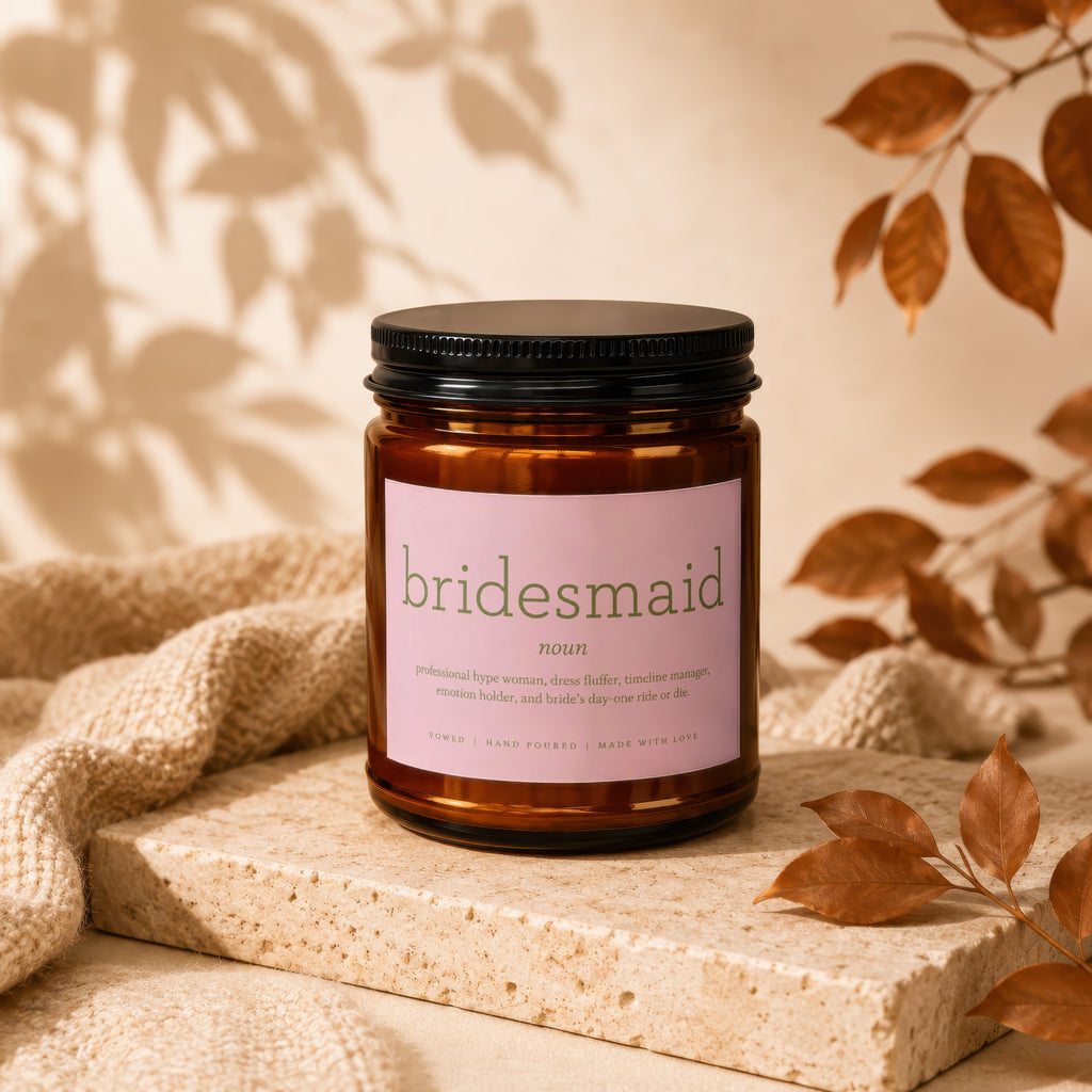 Amber glass candle with pink label that says "bridesmaid noun" and humorous definition.