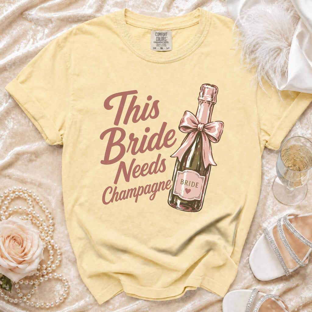 Yellow t-shirt with "This Bride Needs Champagne" text and champagne bottle graphic.