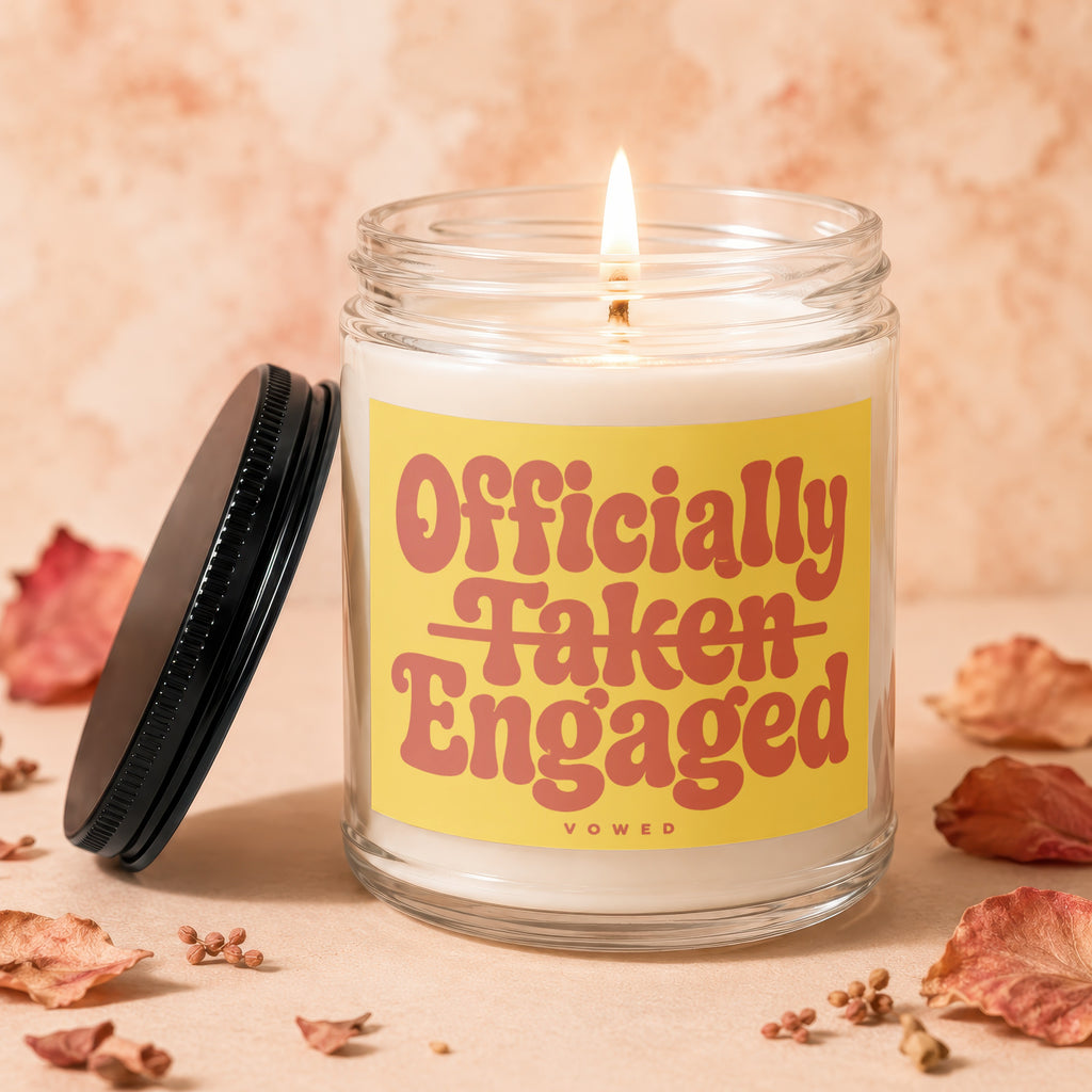 Glass candle with yellow label reading "Officially Taken Engaged" and the word "VOWED".