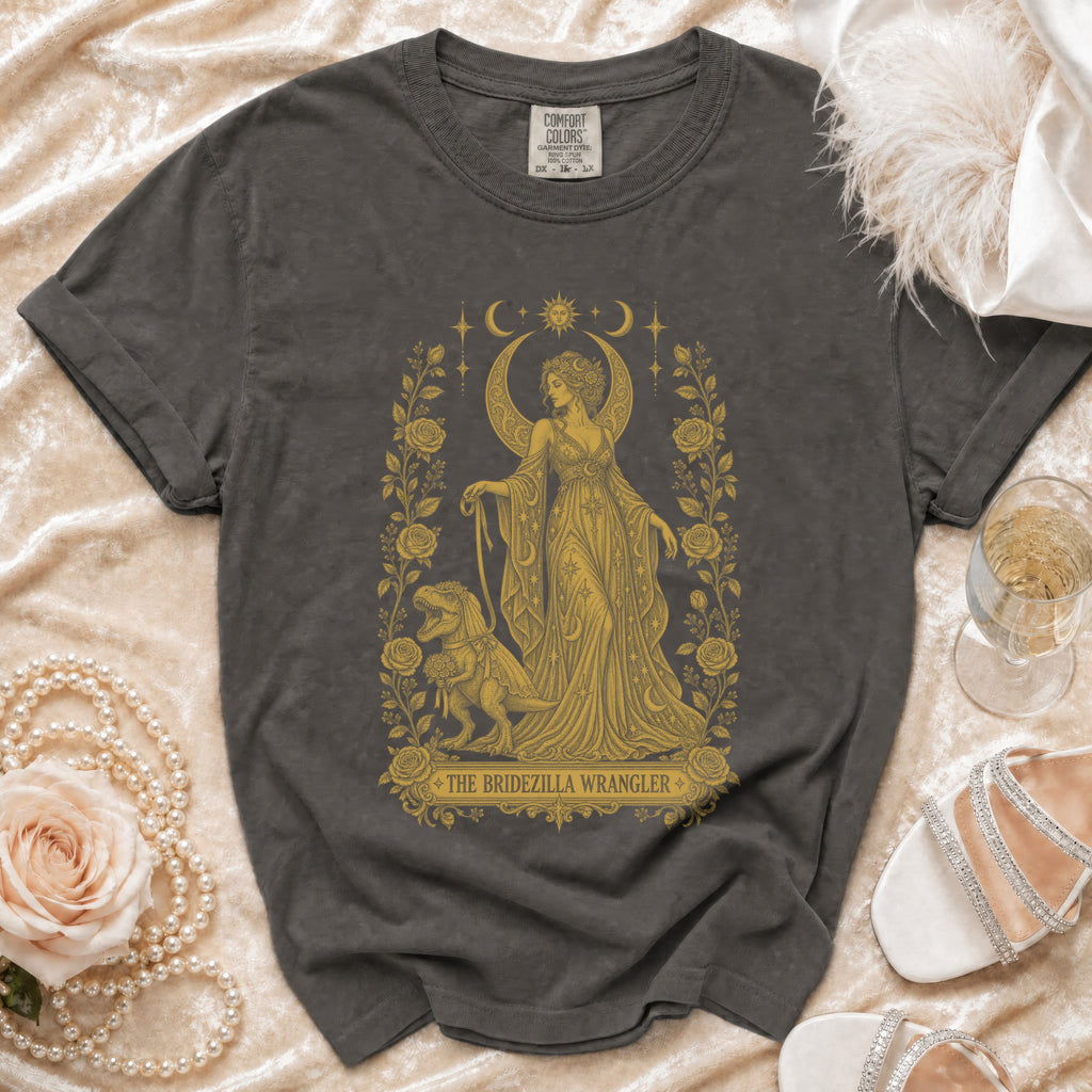 Dark grey t-shirt with gold graphic of a woman and T-Rex, reads "The Bridezilla Wrangler".