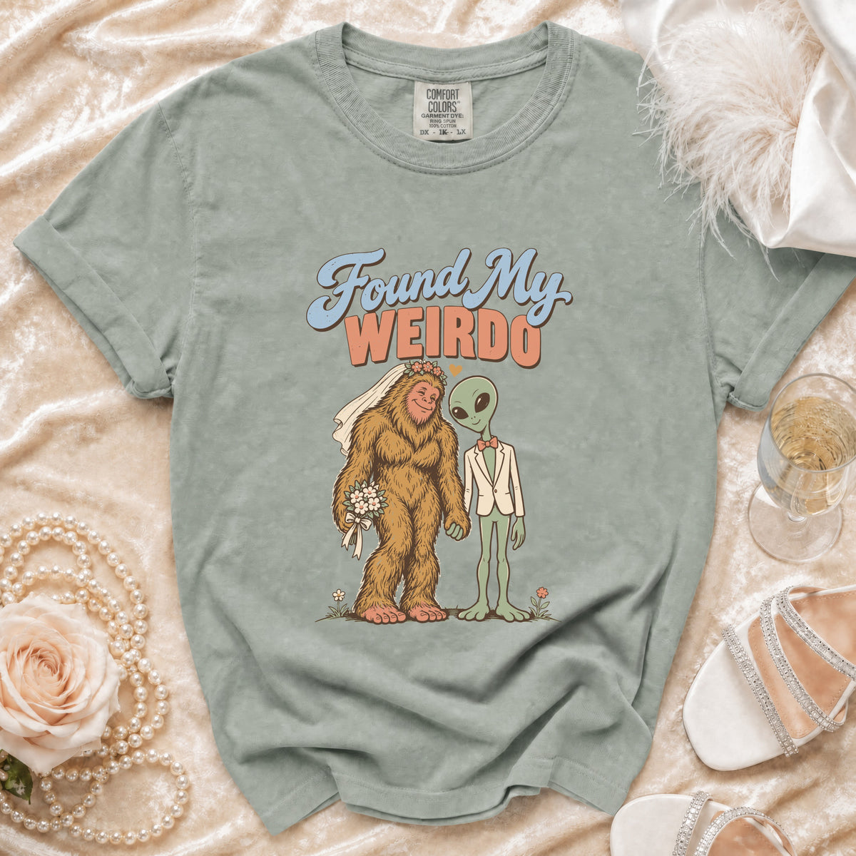 Green t-shirt with Bigfoot bride and alien groom graphic saying "Found My Weirdo."