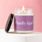 Glass candle with lit wick and black lid, reads "Finally legal"