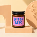 Brown glass candle with "WIFED UP." text on a pink label.