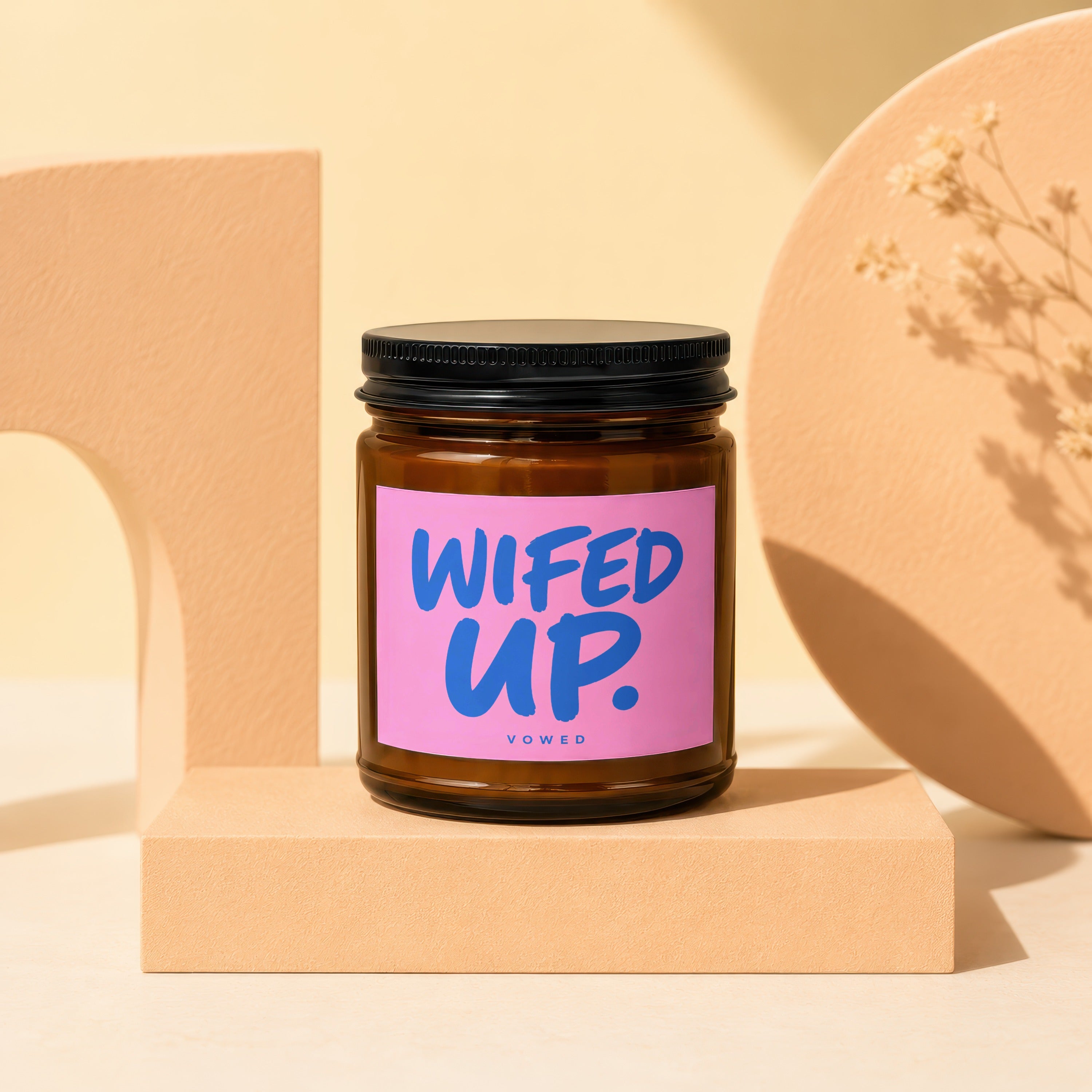 Brown glass candle with "WIFED UP." text on a pink label.