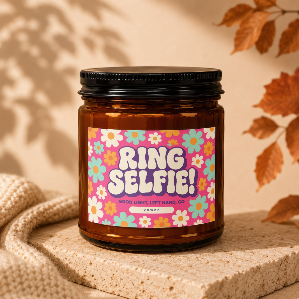 Brown glass candle with "RING SELFIE!" text and floral pattern on pink label.