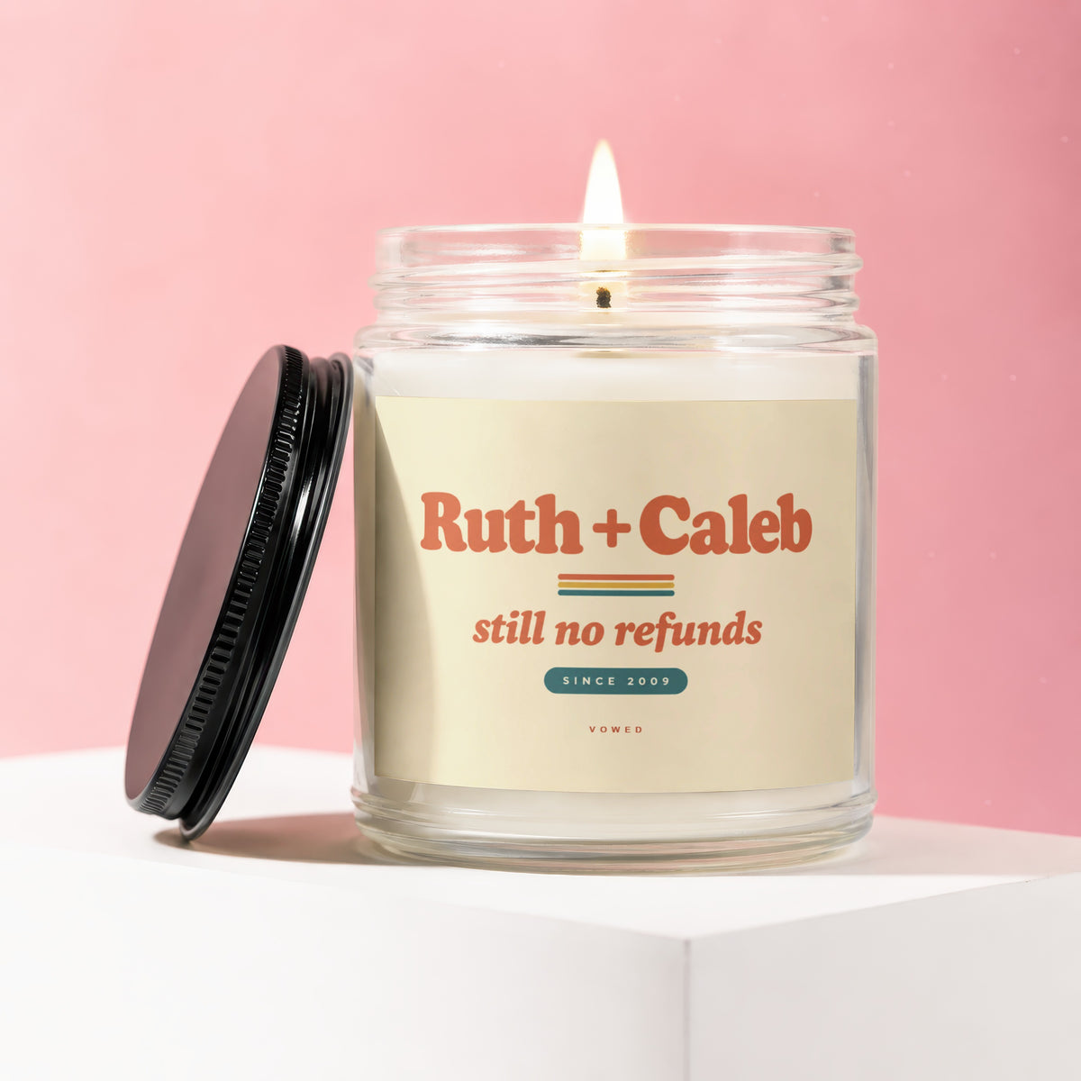 Glass candle with "Ruth + Caleb still no refunds SINCE 2009" on label.