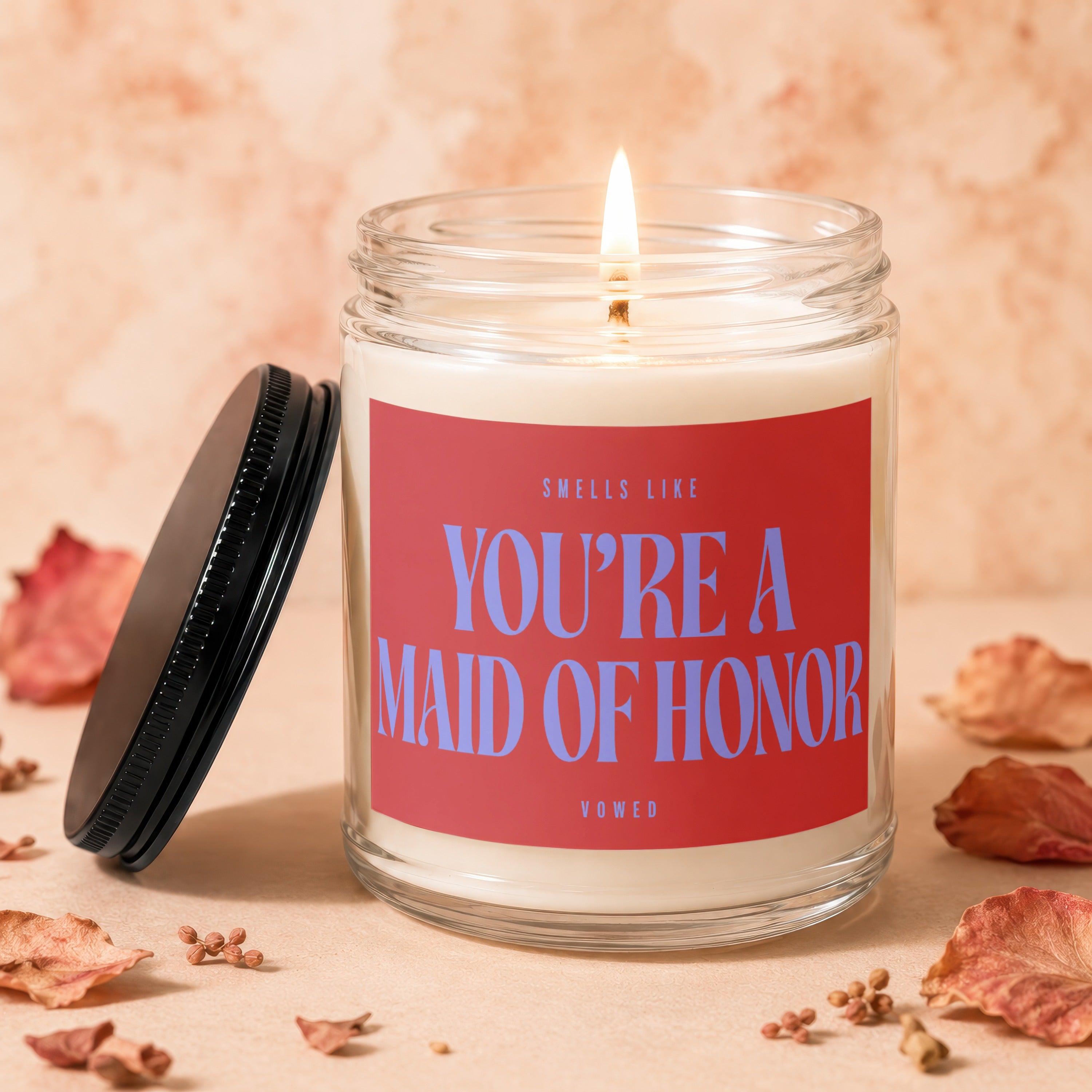 Jar candle with "Smells like you're a maid of honor" text, lid beside it.