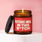 Amber candle with a lit wick and a red label reading "Smells Like Future Mrs. in This B*tch".