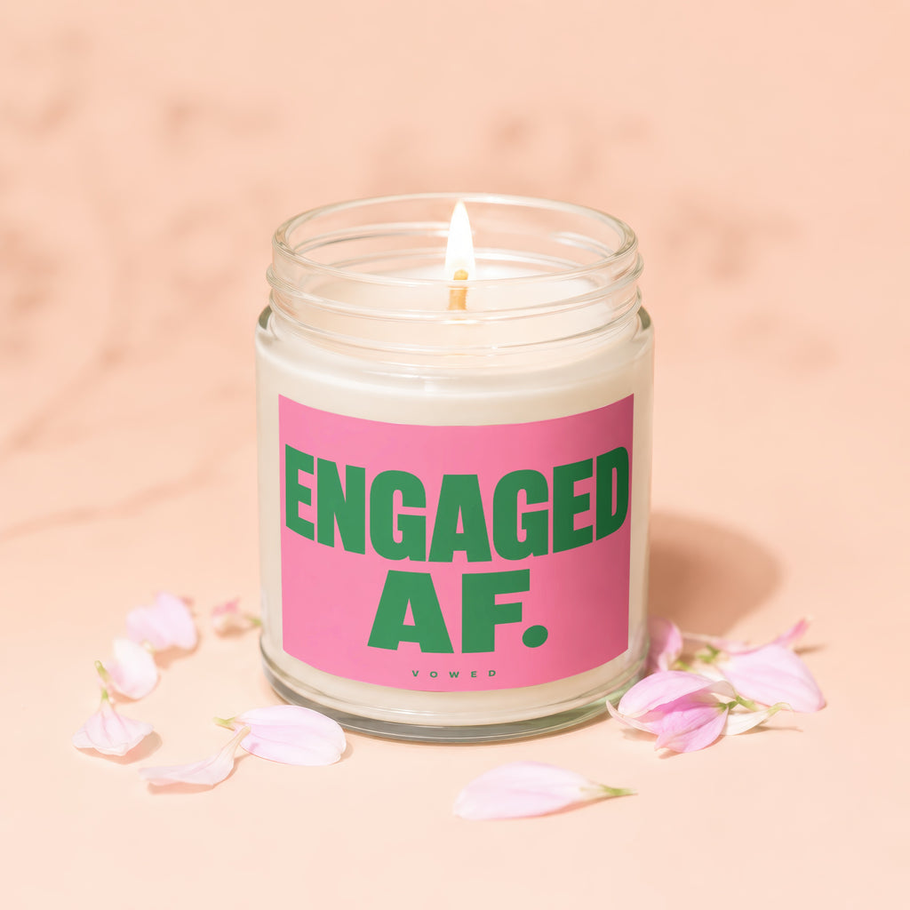 Candle with pink label that says "ENGAGED AF." surrounded by flower petals.